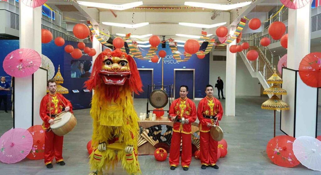 Traditional lion dancer for hire with Chinese musicians at a public setting.