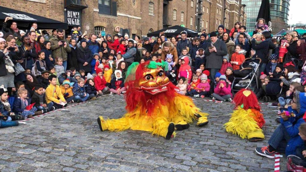 Community watching lion dance performance in London street.
