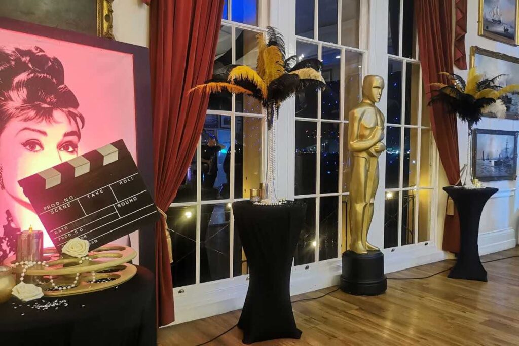 Hollywood themed event space at London venue with movie reel table centrepieces, feather table centrepieces and golden statue.