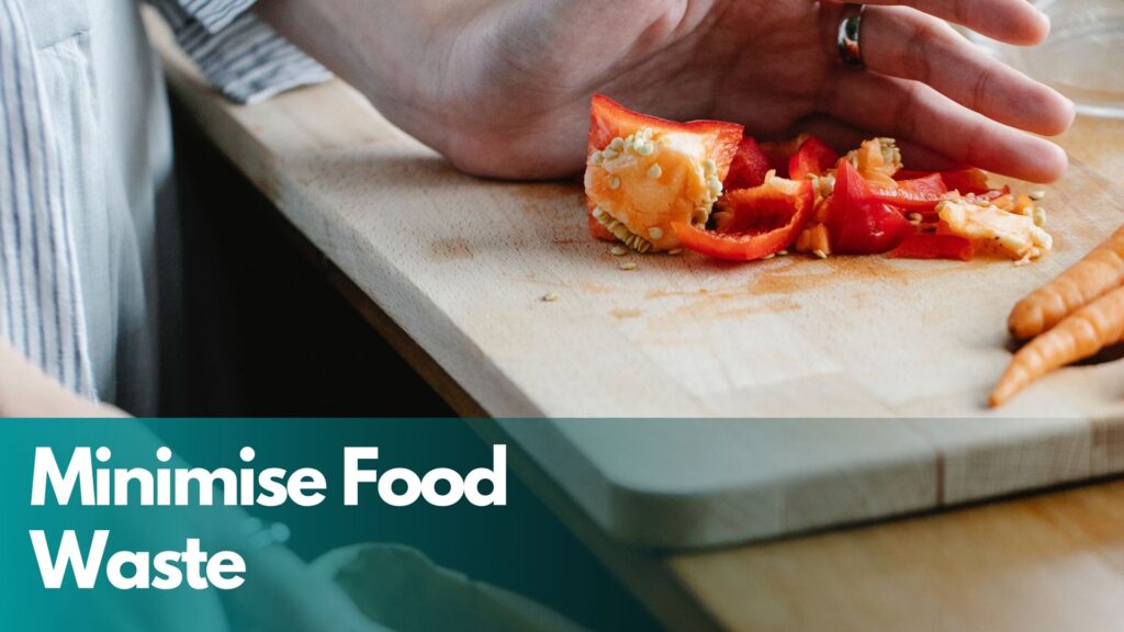 Red pepper being scooped from chopping board into waste bin.