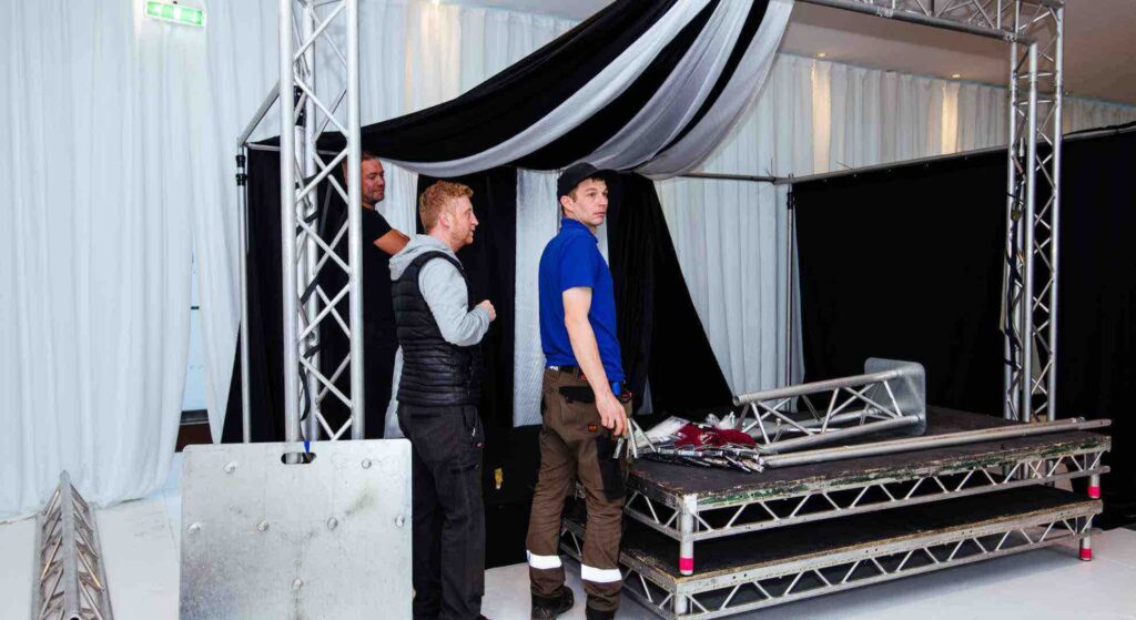 A team of event builders putting together black and white draping at a venue for a custom construction.