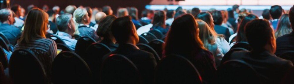 Attendees watching sitting and watching a sustainable conference.