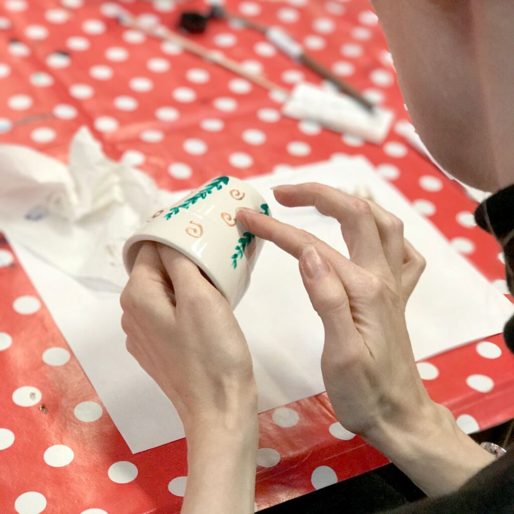 A lady is putting finishing touches to her painted pot during workshop