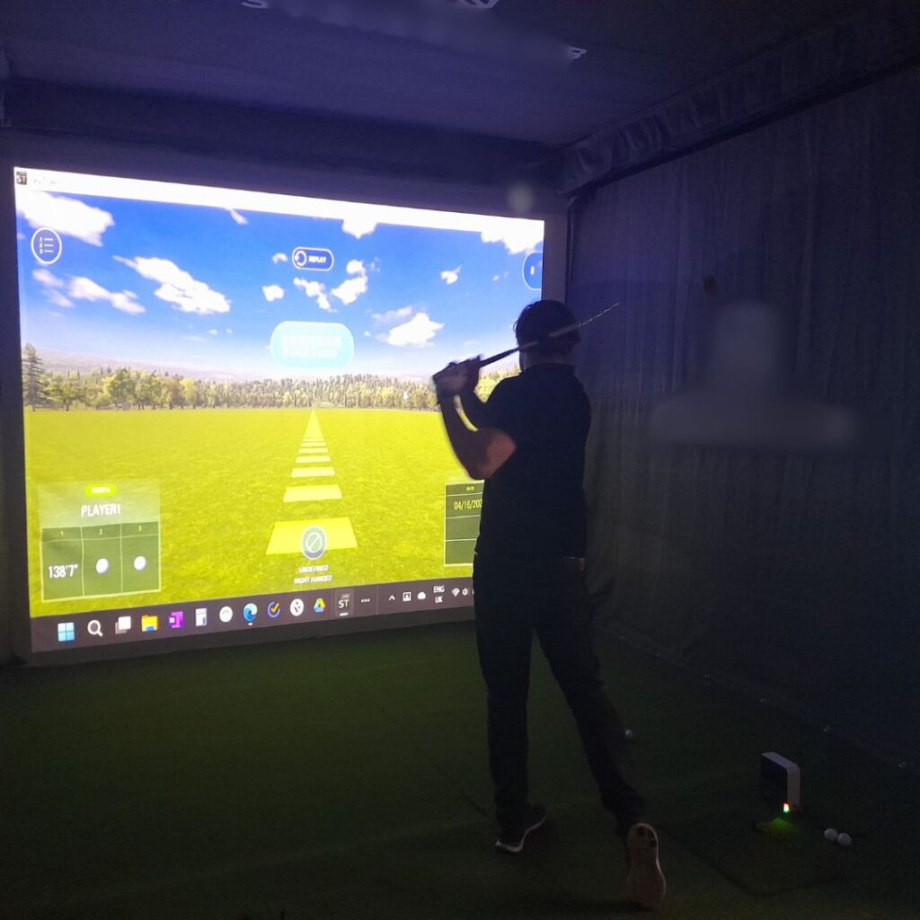 Man taking swing at golf simulator at an event.