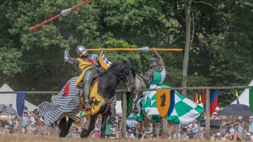 A jousting knight is knocked off his horse in a battle