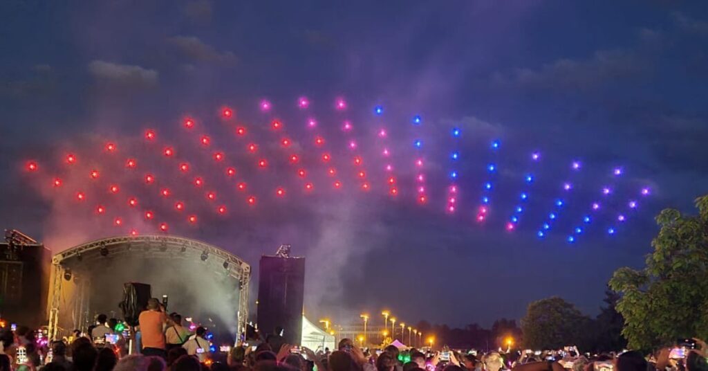 Red and blue LED drones flying over the heads of guests to create pattern in the air during concert event