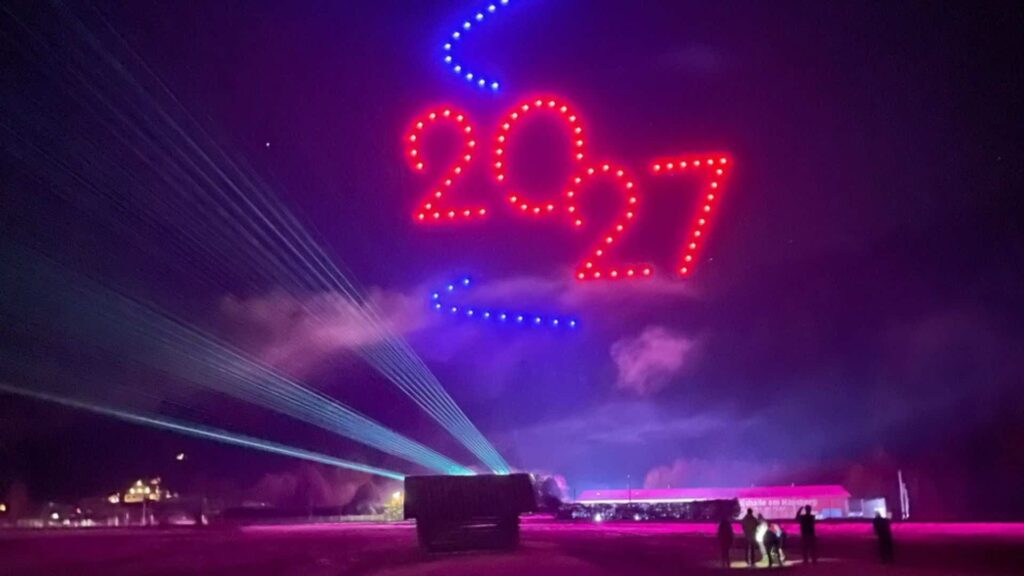 Drone flying in formation to create the year 2027 in red and blue text