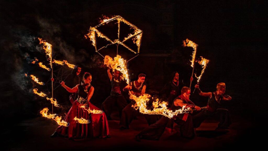 Fire performers glow in the dark dressed in tribal wear