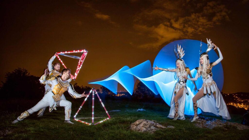 Two glow performers on stage with blue projection background