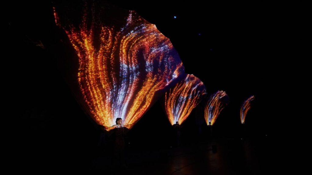 A holographic 3d projection show of fire like patterns over a dancer
