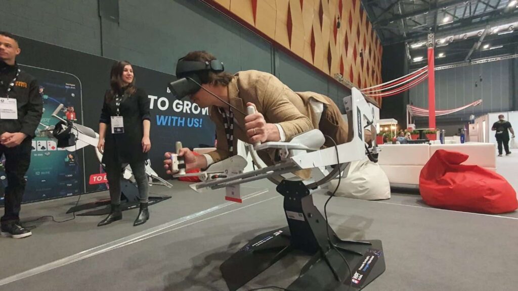 Man wearing VR headset and laying on his front in machine to control himself while flying in virtual reality