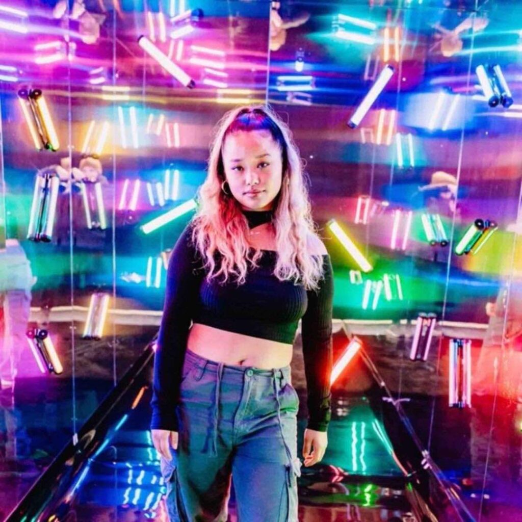 A girl poses inside an LED photo tunnel full of colour