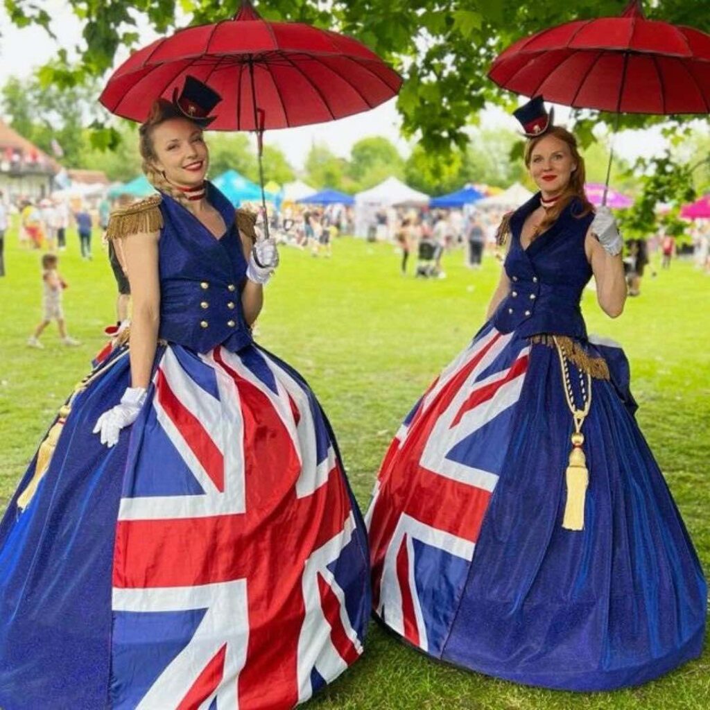 Two ladies dressed in union jack dresses as walkabout entertainment with umbrellas