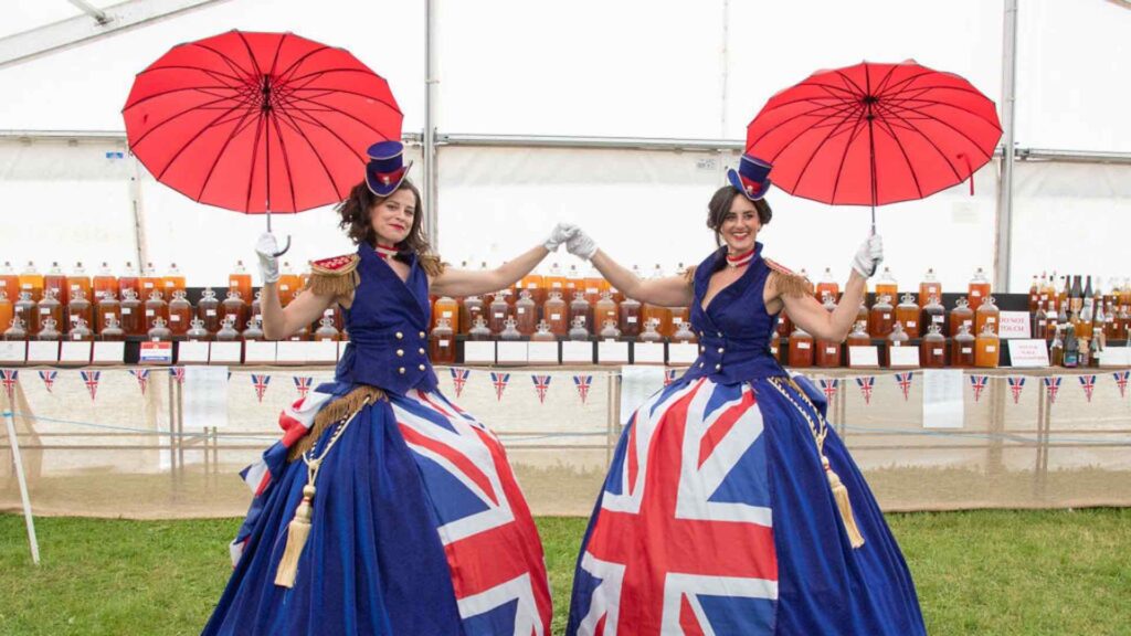 Two ladies dressed in union jack dresses as walkabout entertainment with umbrellas