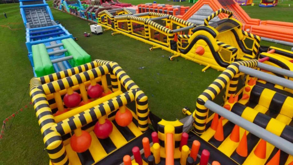 A birdseye view of a yellow and black inflatable obstacle course with red obstacles