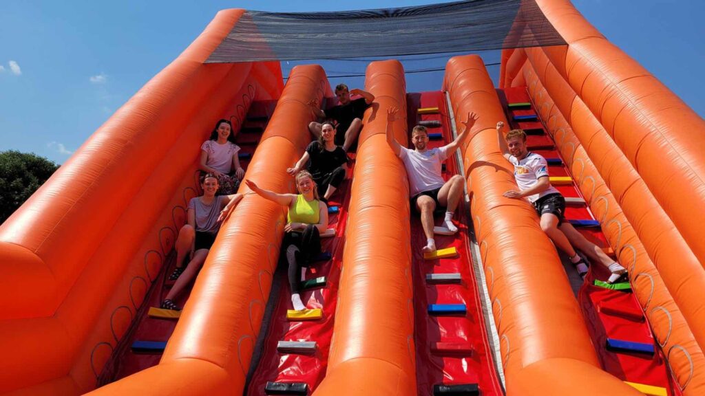 An inflatable red slide with participants sliding down.