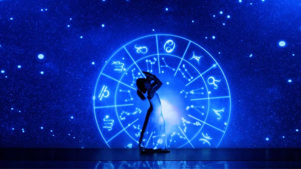 A dance in front of an astrology wheel projection interacts on stage