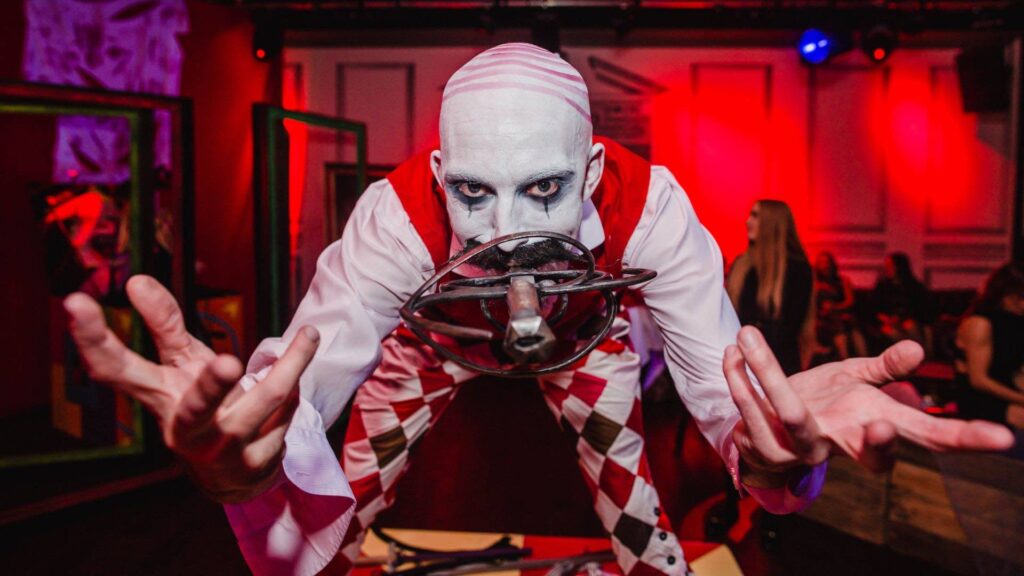 Halloween Themed Entertainment performing to the camera with sword in his mouth dressed in a creepy carnival theme