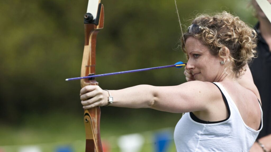 Lady playing archery at an Olympic themed corporate event as a team building exercise.