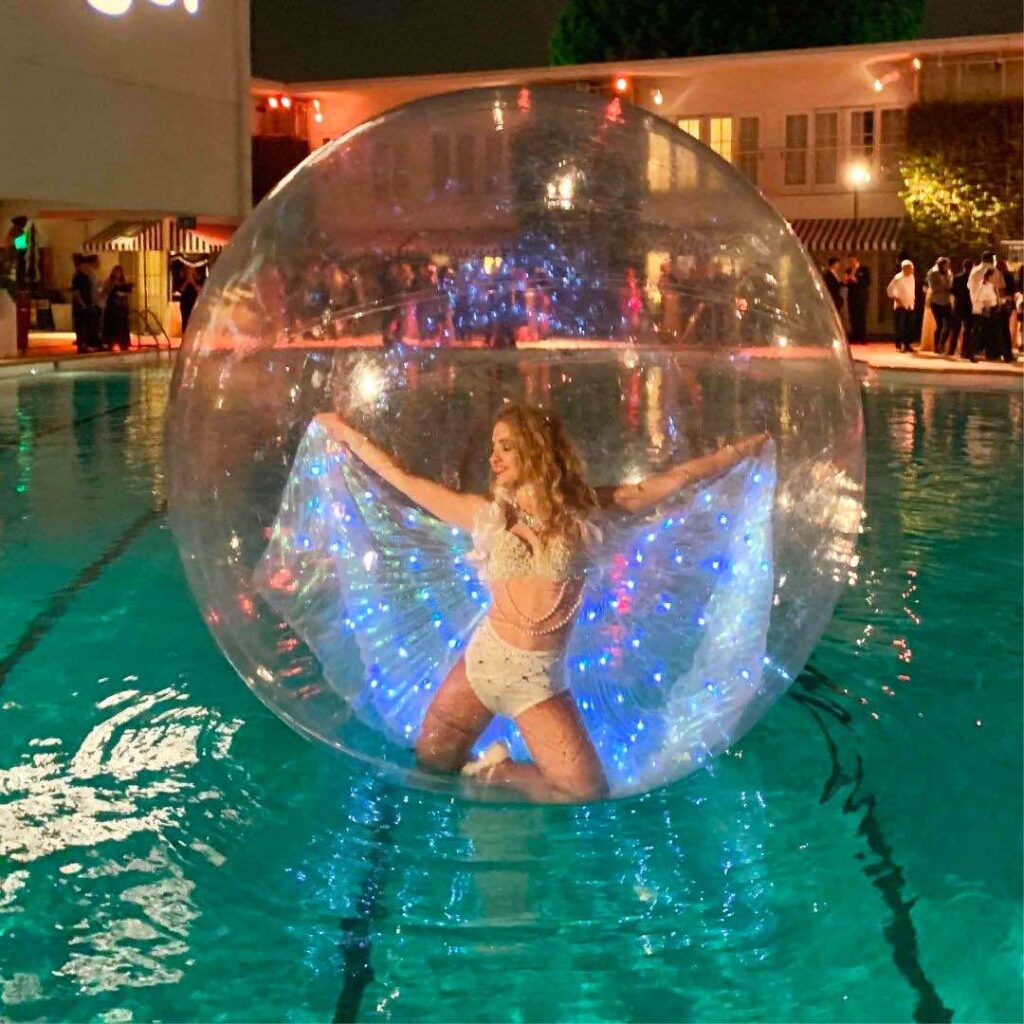 An eye catching lady inside a giant sphere bubble floating on water performing a dance routine