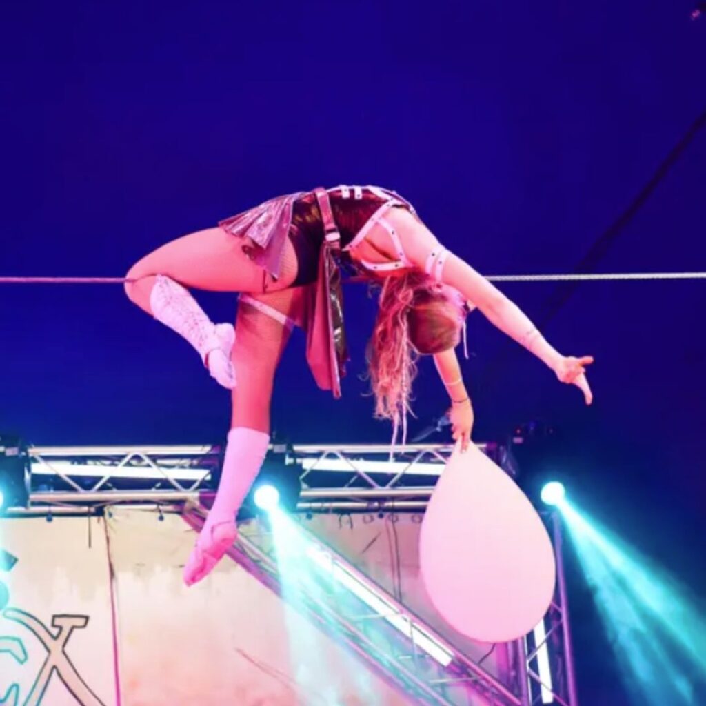 A highwire tightrope walker during a bespoke circus show performance creates suspense