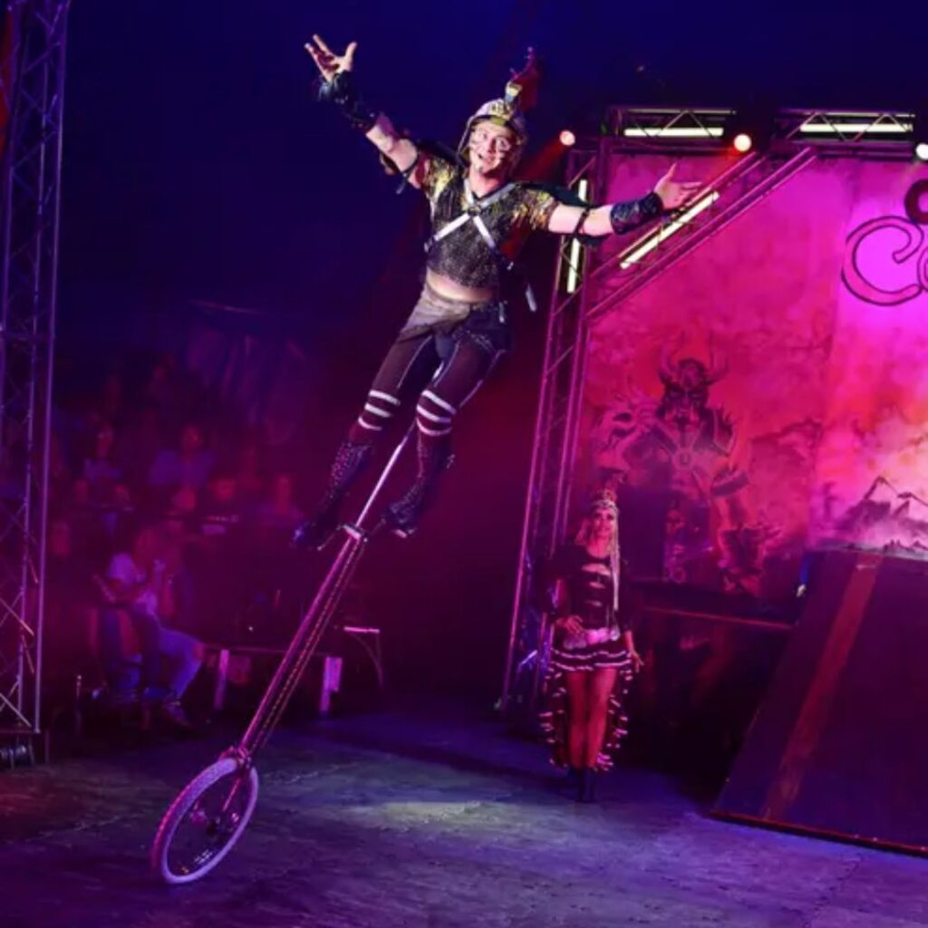 Circus performer on unicycle performing on stage at an event.