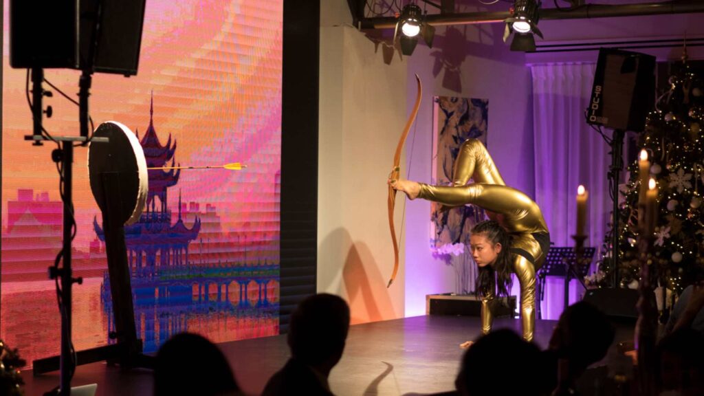 A bow and arrow contortion act featuring stunning stage show as she fires at a target with her feet.