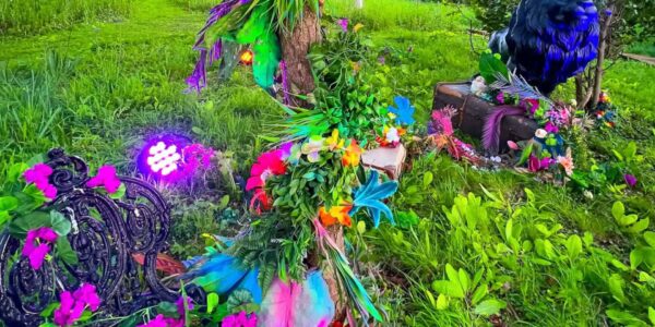 Colourful artificial flowers and foliage on grass in a magical garden setting.