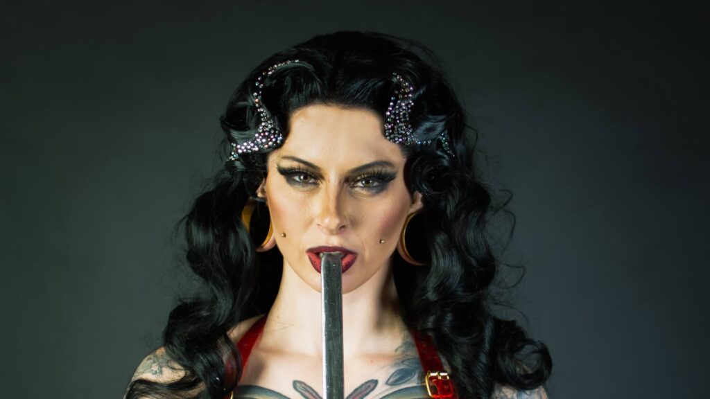 A female sword swallower with black hair shown midway swallowing her sword
