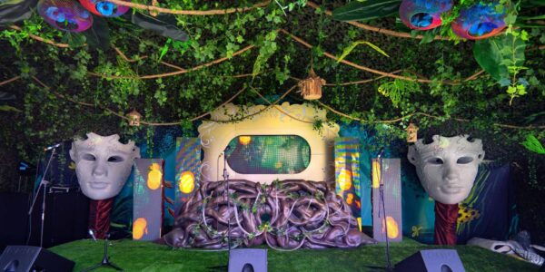 A garden-inspired stage arrangement, filled with vibrant colors, textured plants, and an immersive natural ambiance with a central focus 3d projection screen