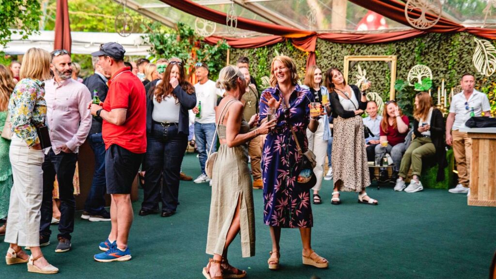 Guests enjoying conversation during the daytime in a marquee designed for our enchanted garden themed event.
