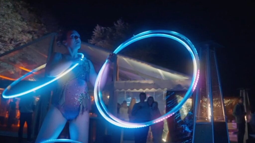 A blue glowing hula hoop ring with an acrobat performing a hula hoop light show