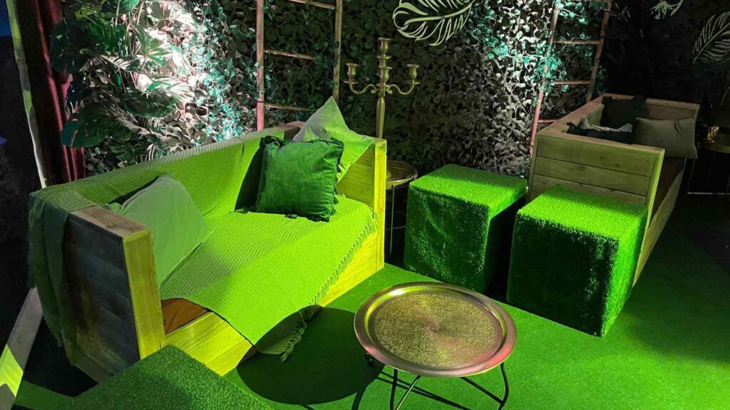 Pallet furniture seating area at night with green lighting projections.