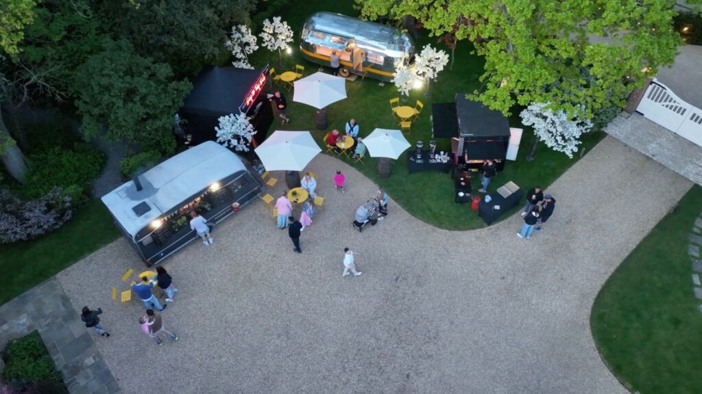 Aerial view of catering area with retro pizza bus, lobster stand, champagne bus and burger van.