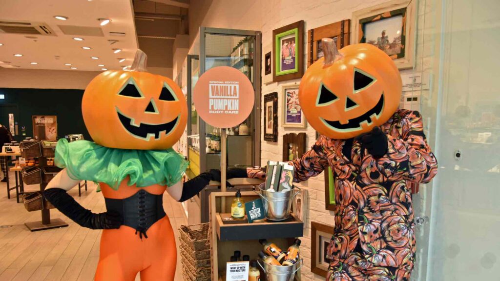 Giant pumpkin-headed performers engaging with visitors at a Halloween-theme