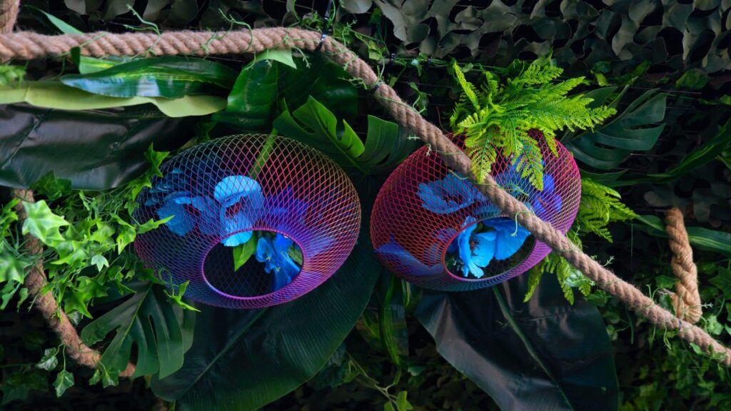 Purple and blue flowers in a net hanging from a tree prop