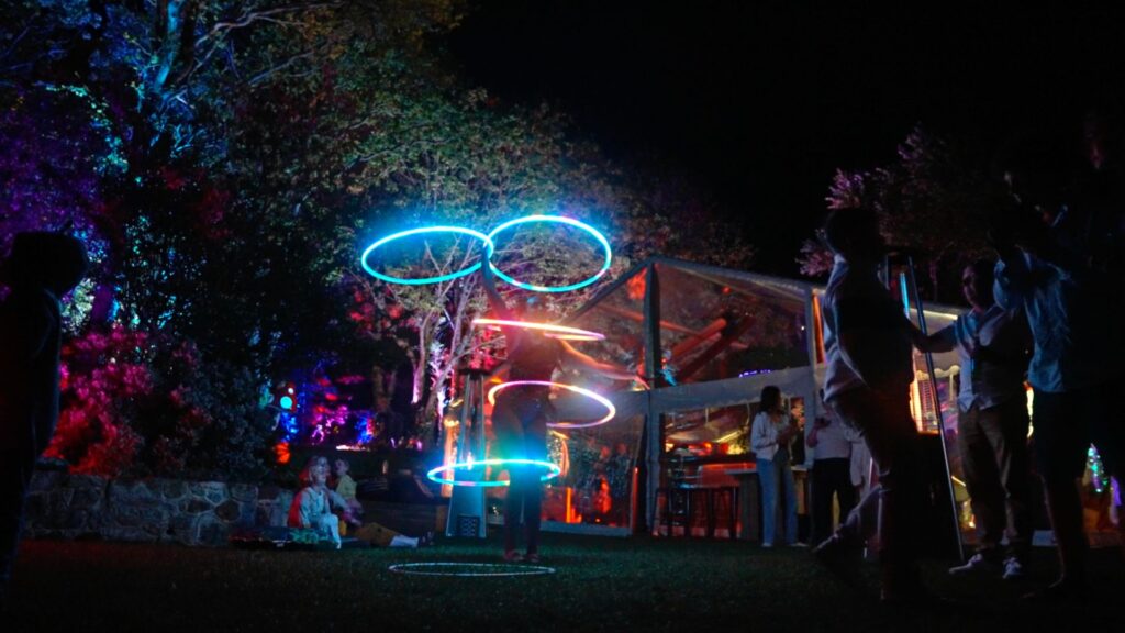 A full scale shot of a dazzling LED hula hoop performer at night time with blue glowing rings