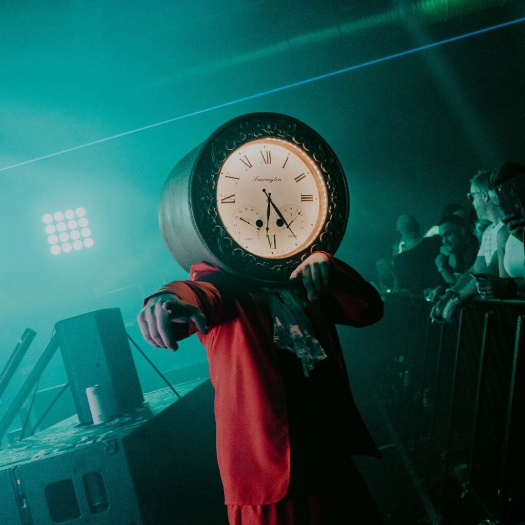 Clock head performer points to the audience during performance