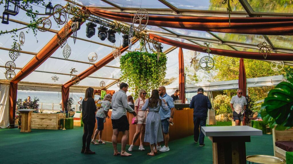 A naturally lit event space showing a translucent marquee with guests inside. 