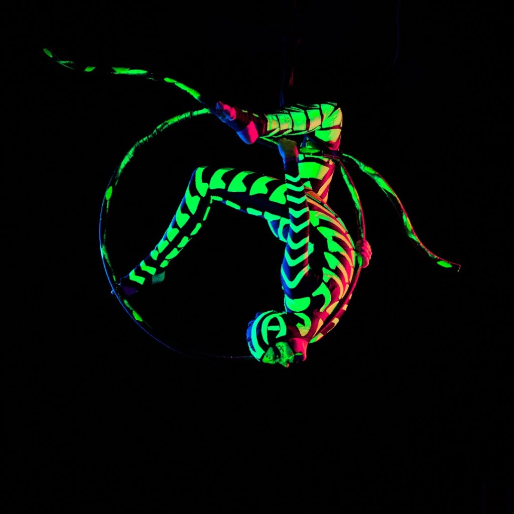 A neon UV hoop aerial performer