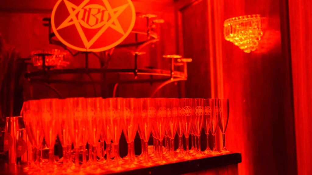Cult-branded event bar with branded cocktail glasses and bespoke 'illuminati' style signs.