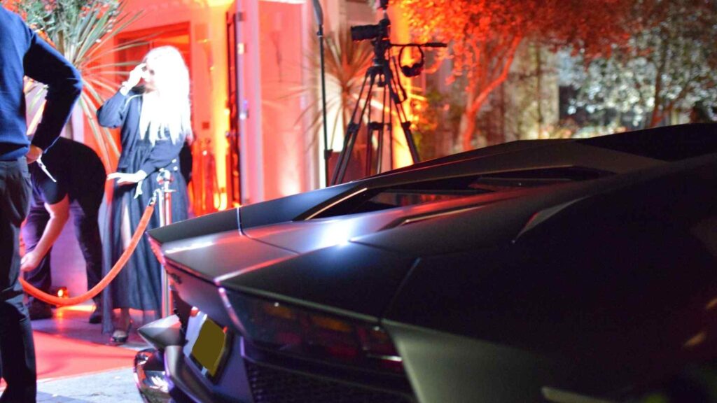 Cult Awakening Halloween mansion party Lamborghini Aventador parked on driveway in front of house.