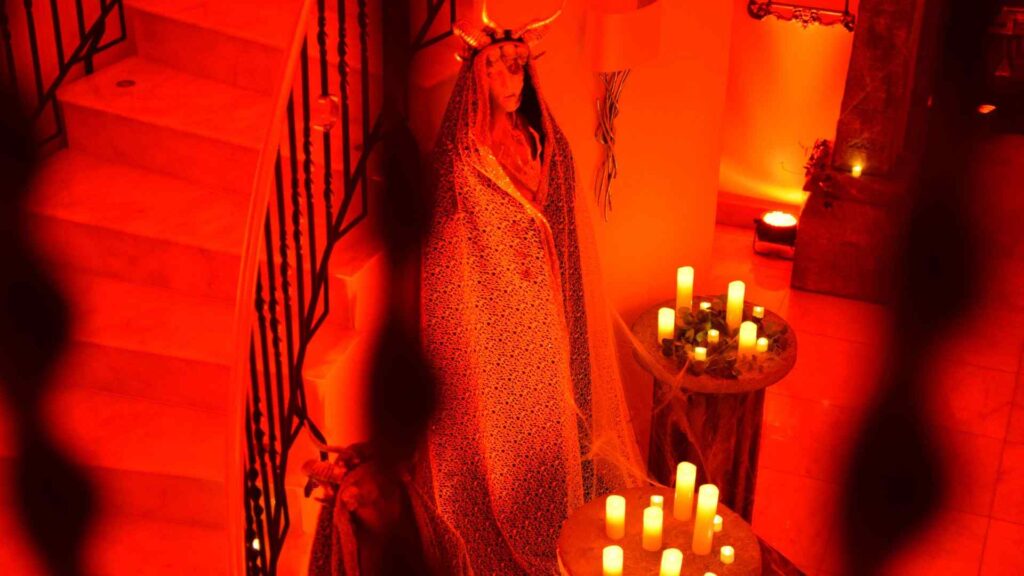 Mysterious statue prop with cape, crown and candles at the bottom of spiral staircase.