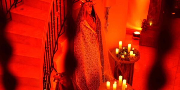 Mysterious statue prop with cape, crown and candles at the bottom of spiral staircase. We completely transformed the hallway and entrance to make an impact on guests as they entered the space.