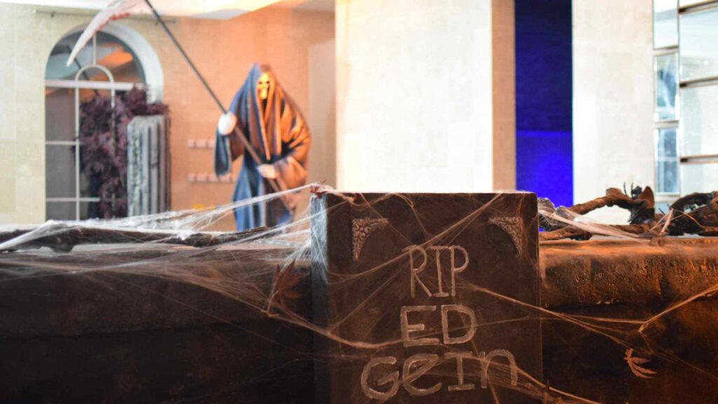 Range of props and decorations in pool area of Halloween mansion party including Grim Reaper and Grave Props.