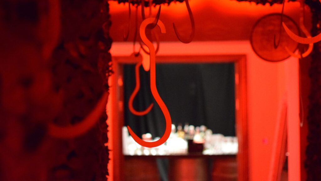 Close-up of hanging hook props used in tunnel entrance to 'Slaughterhouse' room in Halloween mansion party.