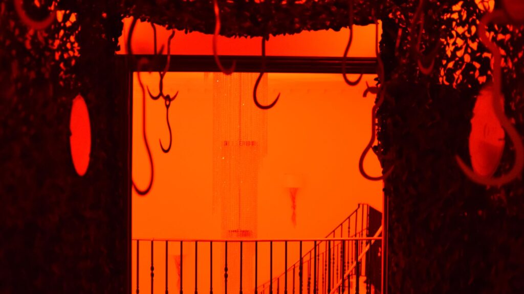 Inside tunnel entrance to 'Slaughterhouse' Halloween mansion party room showing hanging hooks and other props.