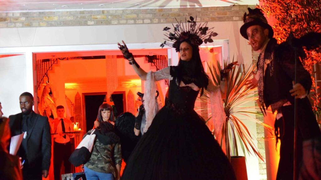 Two Victorian-style stilt walkers greeting guests at Halloween mansion party as they entered the house.