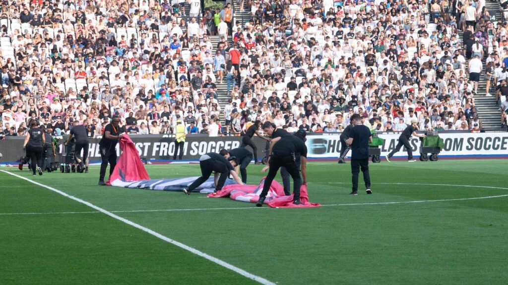 Production team de-rigging performance area on pitch prior to player walkout for second half.