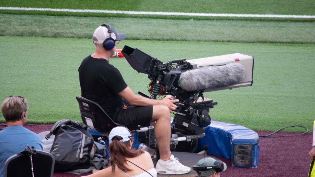 Cameraman pitch side filming the match for the livestream on sports camera.
